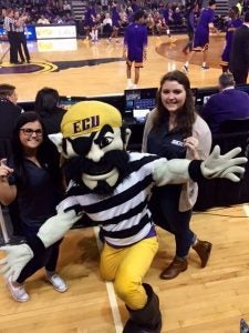 two female students at a basketball game with PeeDee the ECU mascot