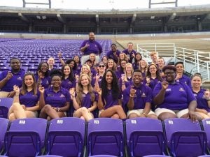 group photo of over two dozen orientation assistants in purple shirts