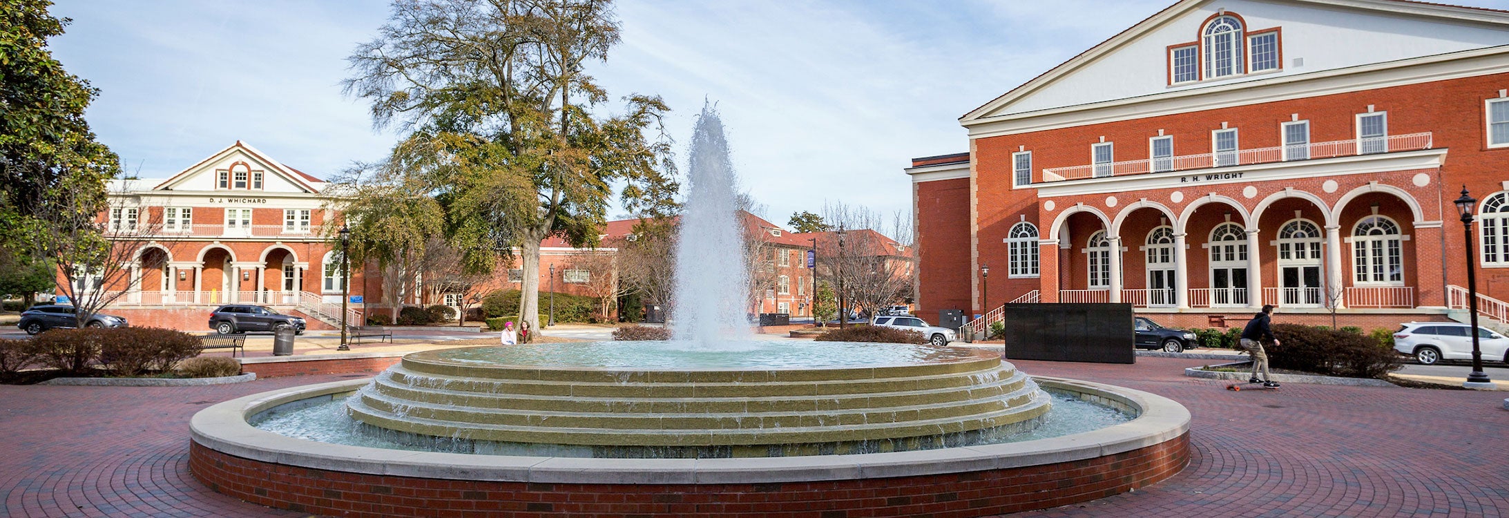 two brick buildings with arched porches and a fountain