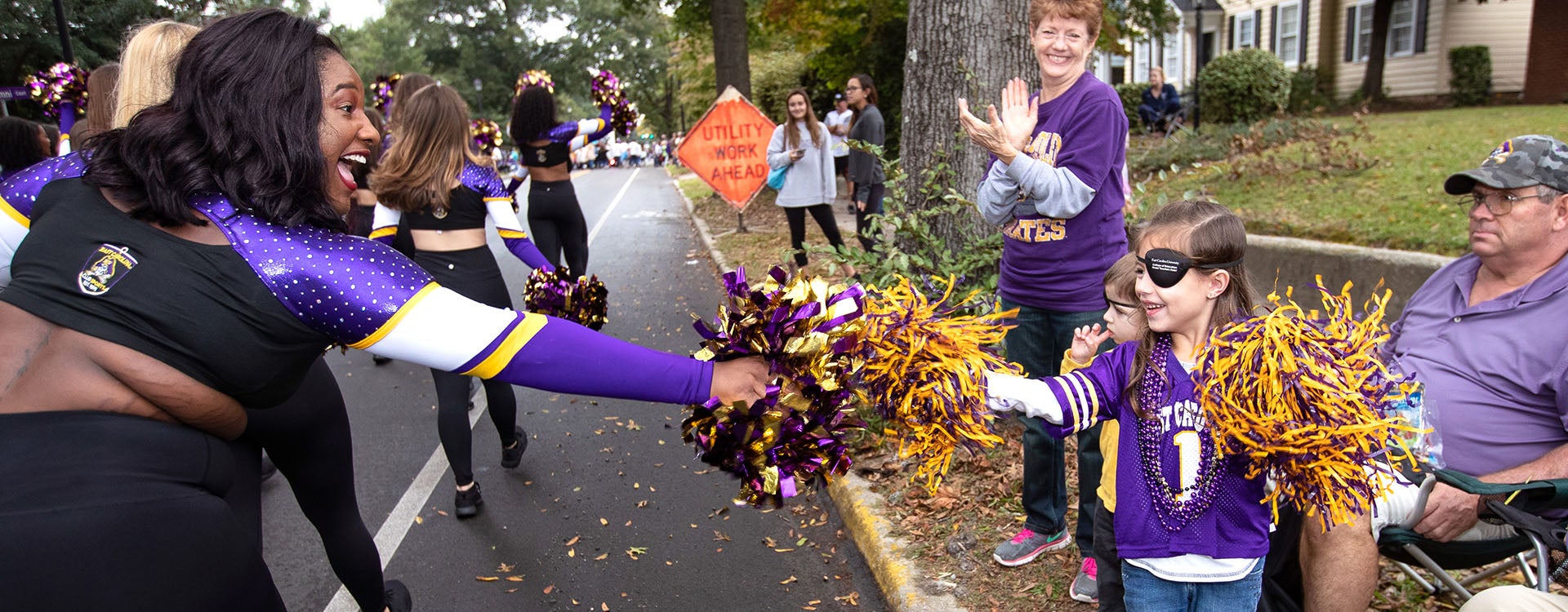 A member of the ECU Club Dance team shares a moment with a young Pirate fan during the Homecoming Parade on Saturday morning. (Photography by Rhett Butler)
