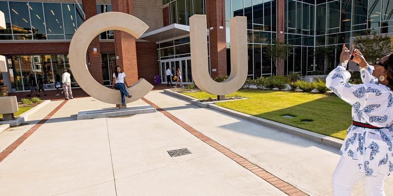 Parent takes a photo at E C U letters in front of the Main Campus Student Center