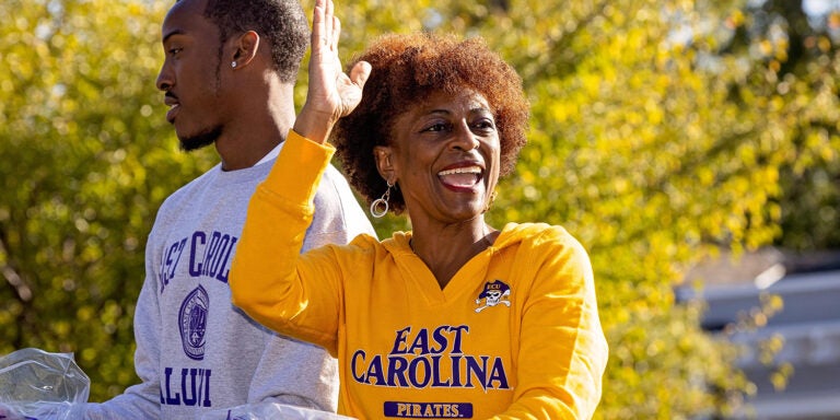 two alumni wave to fellow Pirates from a parade float.