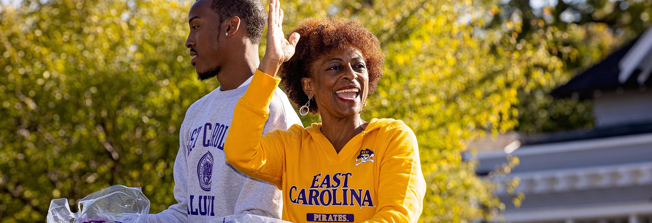 two alumni wave to fellow Pirates from a parade float.