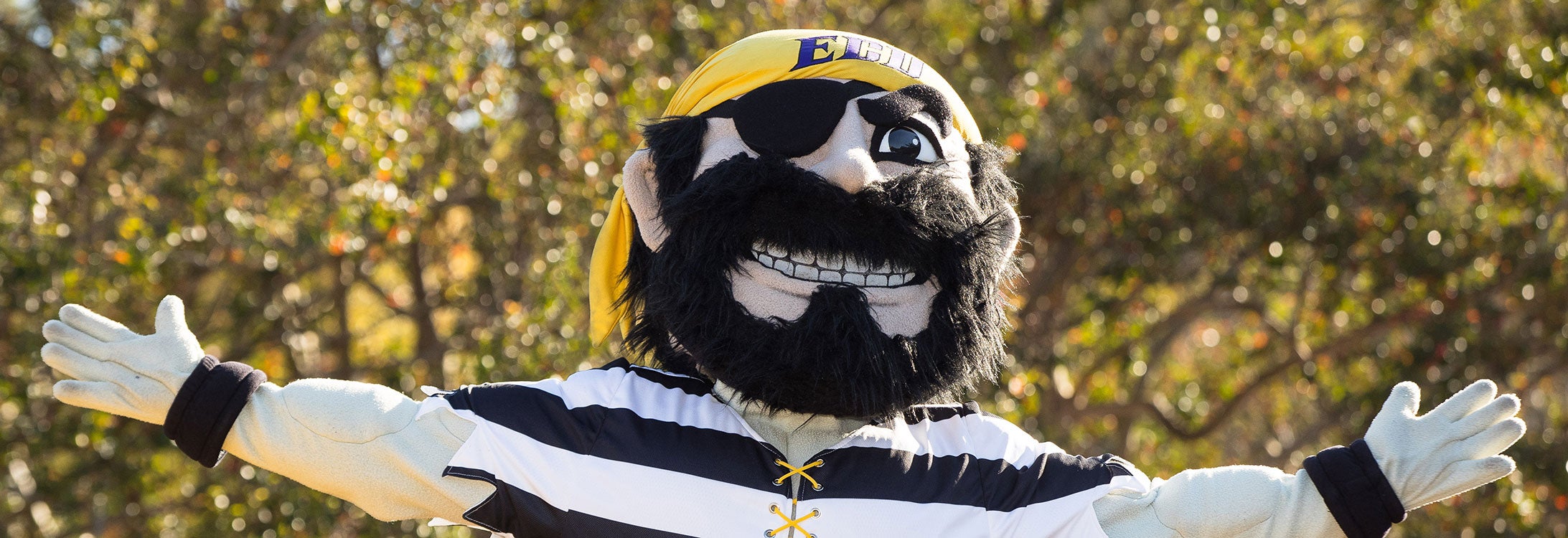 ECU mascot PeeDee the Pirate faces the camera with his arms stretched out as if showing off campus.